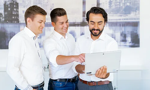 3 Mitarbeiter schaeuen auf einen Laptop